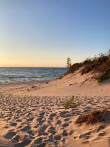 A serene sandy beach with dunes at sunset, offering a calming coastal view.